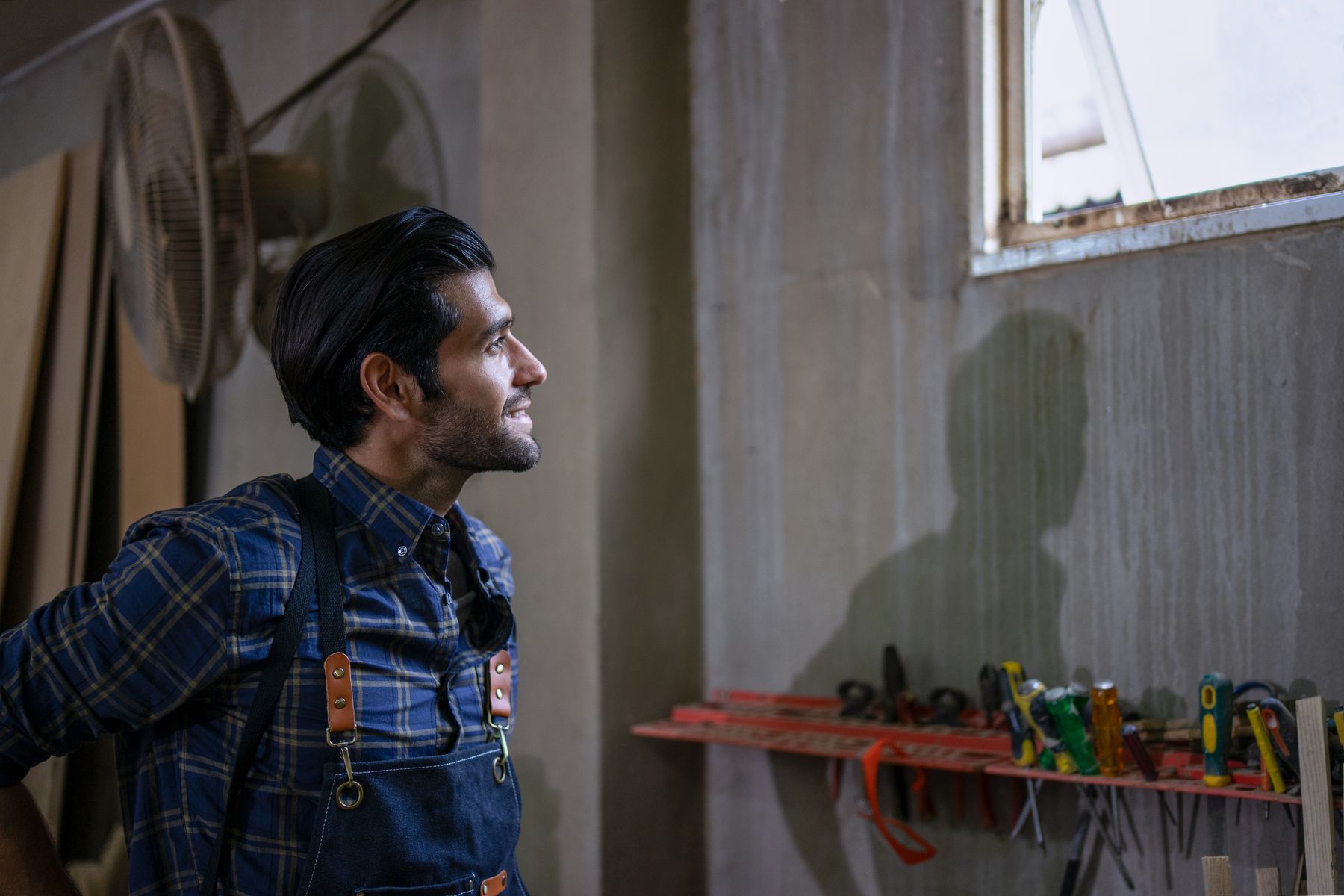 Tradesman smiling as he looks out a workshop window