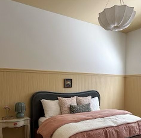 Bedroom with a freshly painted white upper wall and tan paneled lower wall